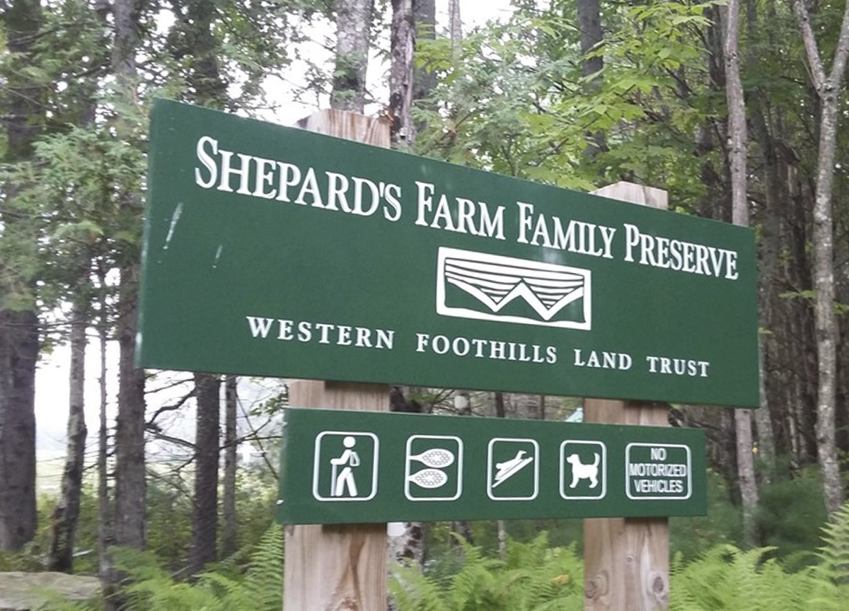 a sign in a wooded area reading "Shepards Farm Family Preserve"