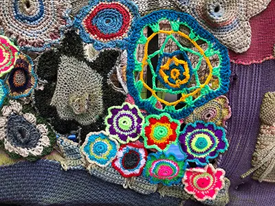 A pile of knit and crochet circles and flowers in different weight yarn and bright colors. 
