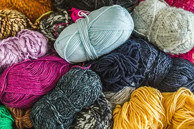 A pile of skeins of yarn in different colors and thicknesses. 