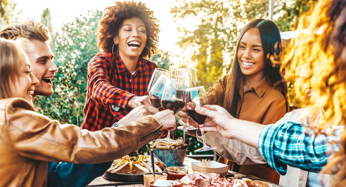 Friends toast with wine glasses in celebration outdoors.