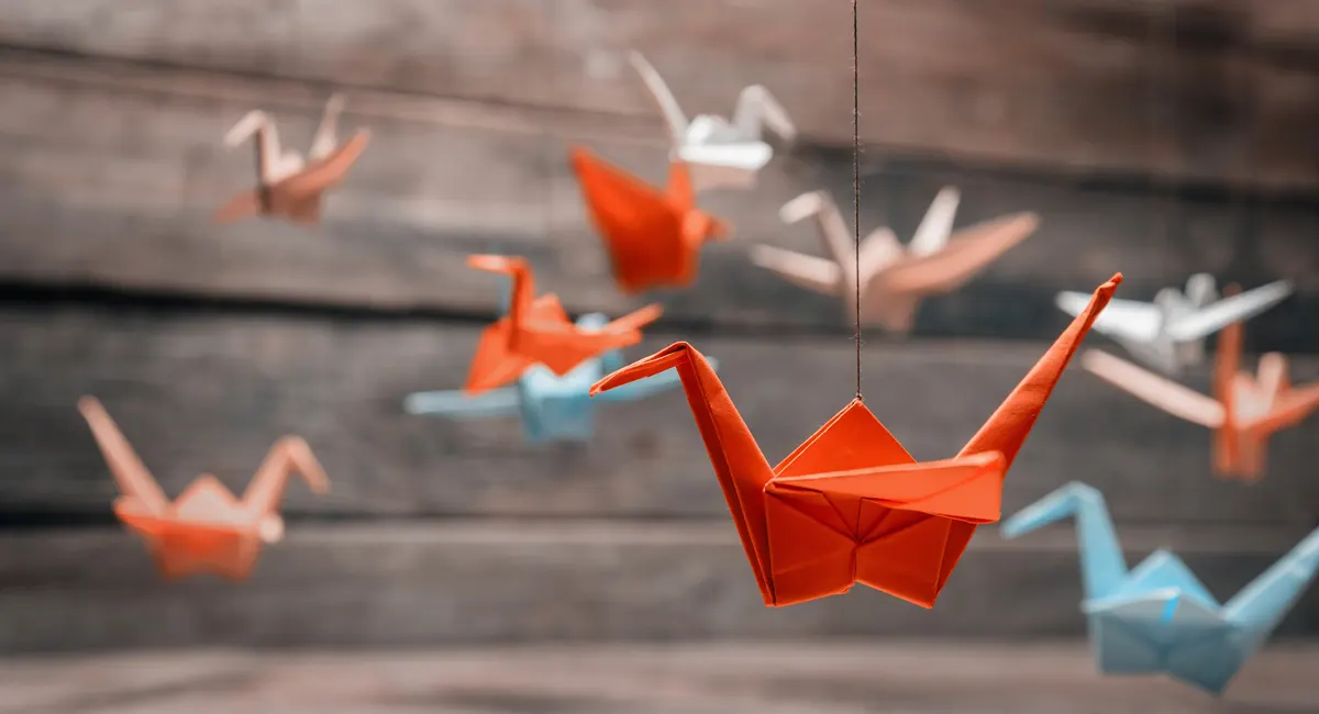 Colorful many origami paper cranes on wooden background