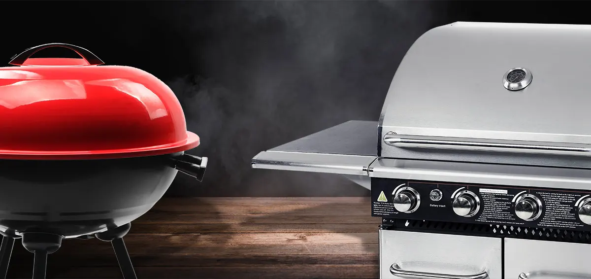 A charcoal grill with red lid and a stainless steel gas grill over a dark wood background 