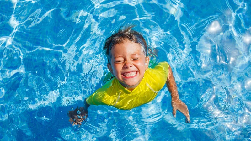 Overhead photo of smiling boy with face sticking out of the pool