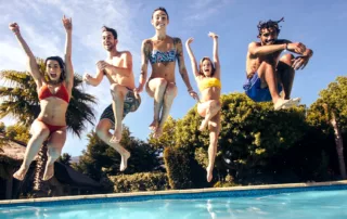 Smiling adults jumping into a pool