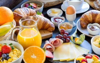 A variety of breakfast food is laid out on a wooden table.