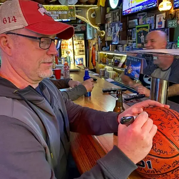 Man signing basketball at a bar