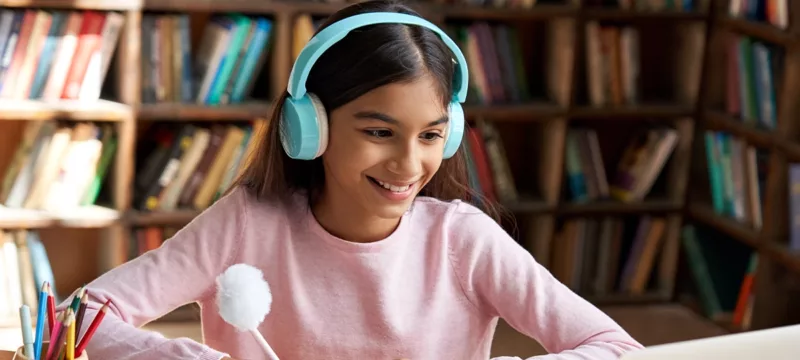 A young girl wearing headphones attends a virtual class.