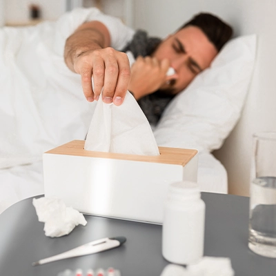 Sick man in bed reaching for tissue