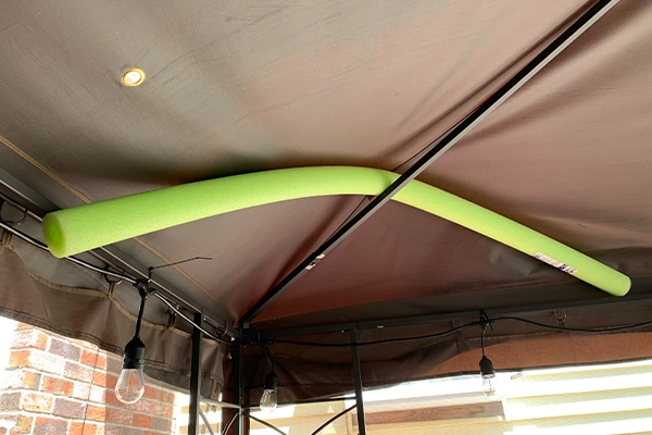 A pool noodle tucked inside the roof of a gazebo