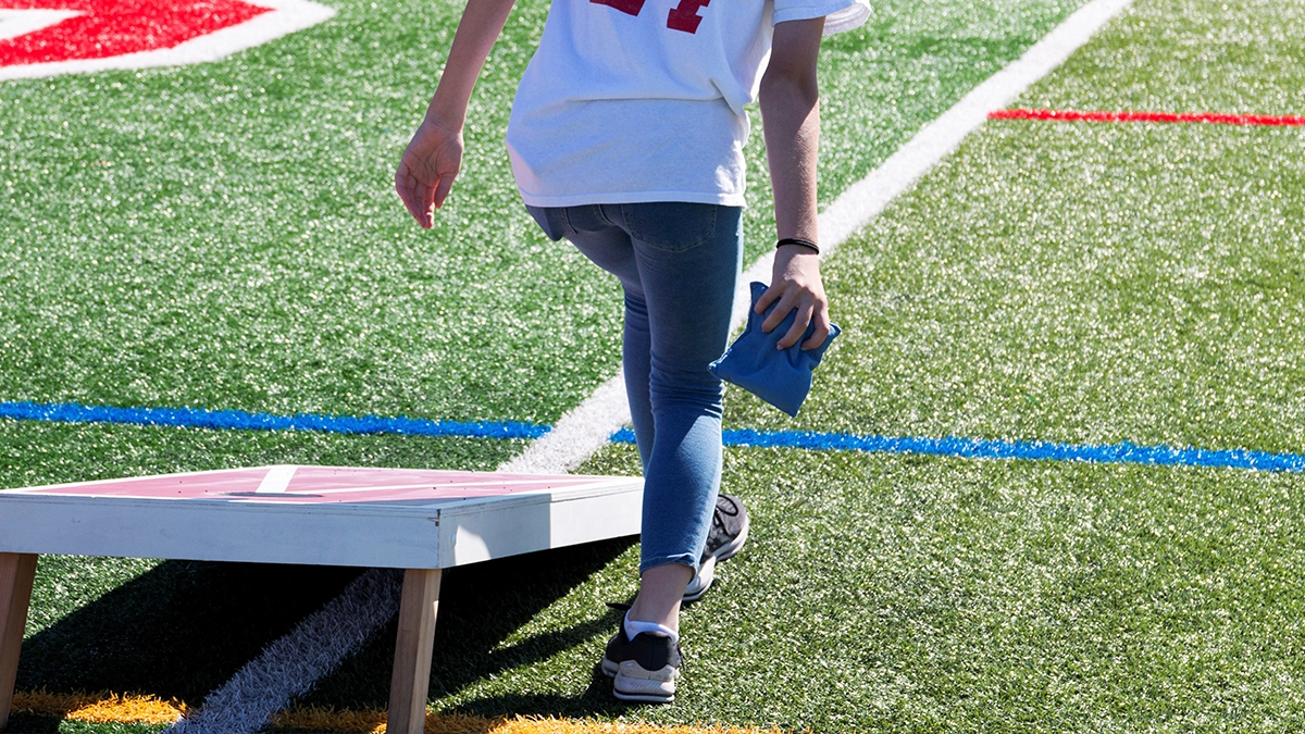 A person playing cornhole on a football field.