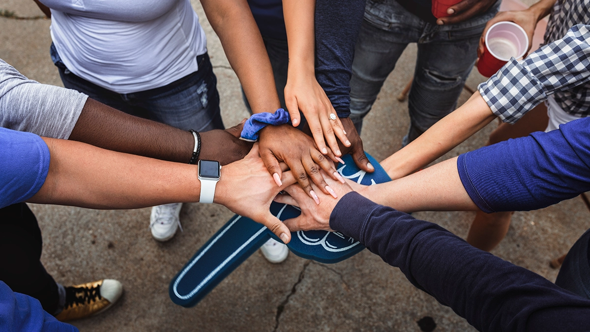 A group huddles together with hands in the middle.