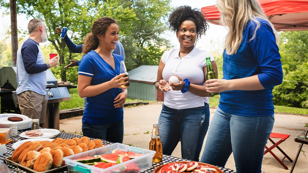 Three women talking and smiling at a tailgate party.