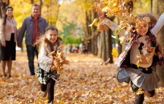 Parents watch kids throwing leaves into the air
