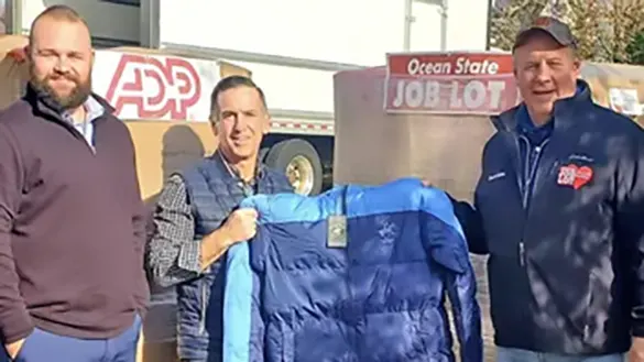 David Sarlitto, Executive Director OSJL Charitable Foundation with Brian Gates, Director Bookwell Travel, display some Buy-Give-Get Coats for veterans in need.