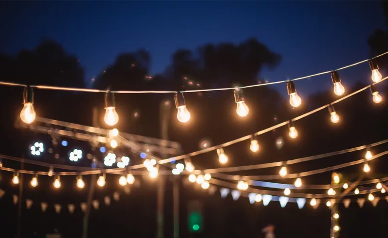 Multiple strands of string lights lighting up a patio at night.