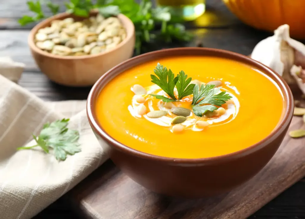 Side view of pumpkin soup in a plastic bowl.