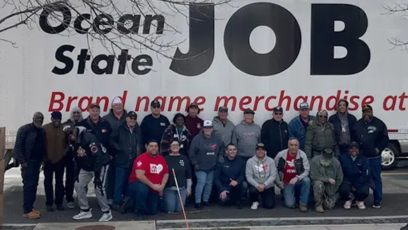 Ocean State Job Lot donation of coats for veterans, group picture in front of OSJL tractor trailer.