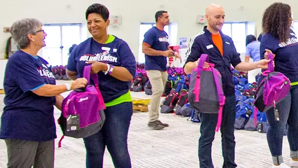 Volunteers fill Buy-Give-Get backpacks for children in need.