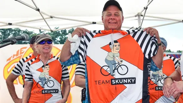 Ocean State Job Lot Charitable Foundation Executive Director David Sarlitto holding a Team Skunky shirt at The New England Parkinson’s Ride in Old Orchard Beach, Maine to benefit The Michael J. Fox Foundation for Parkinson’s Research