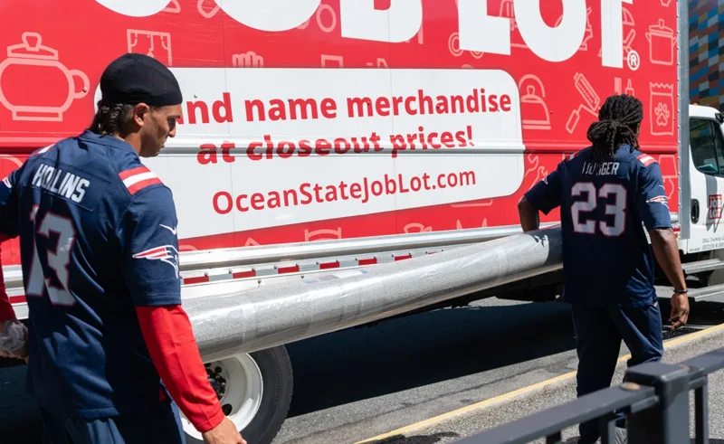 Two members of the New England Patriots carrying a rug.