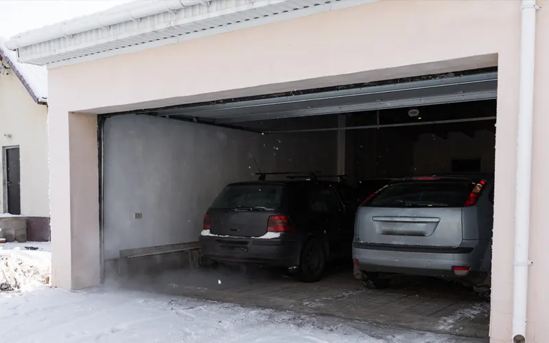 Cars in a home garage during snowfall