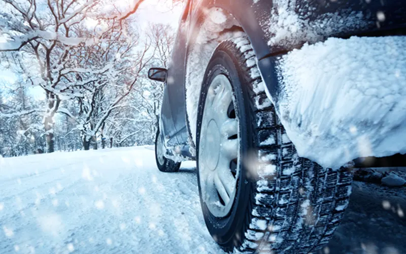 A car driving in the snow showing the tires and the snow on the road