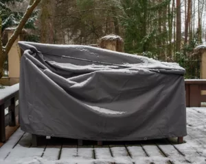 A weather-proof cover on some patio furniture with a light dusting of snow.