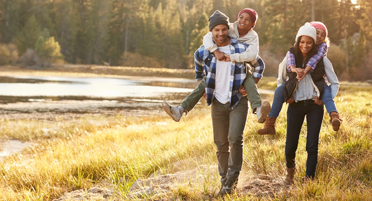 Parents giving children piggyback ride during fall hike