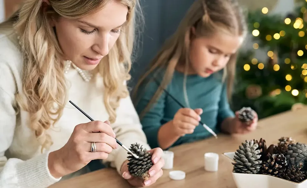 Mother and Young Daughter painting pinecones