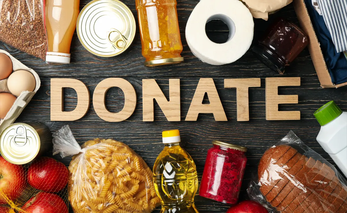 A donate sign with various products to donate to a food pantry surrounding it.