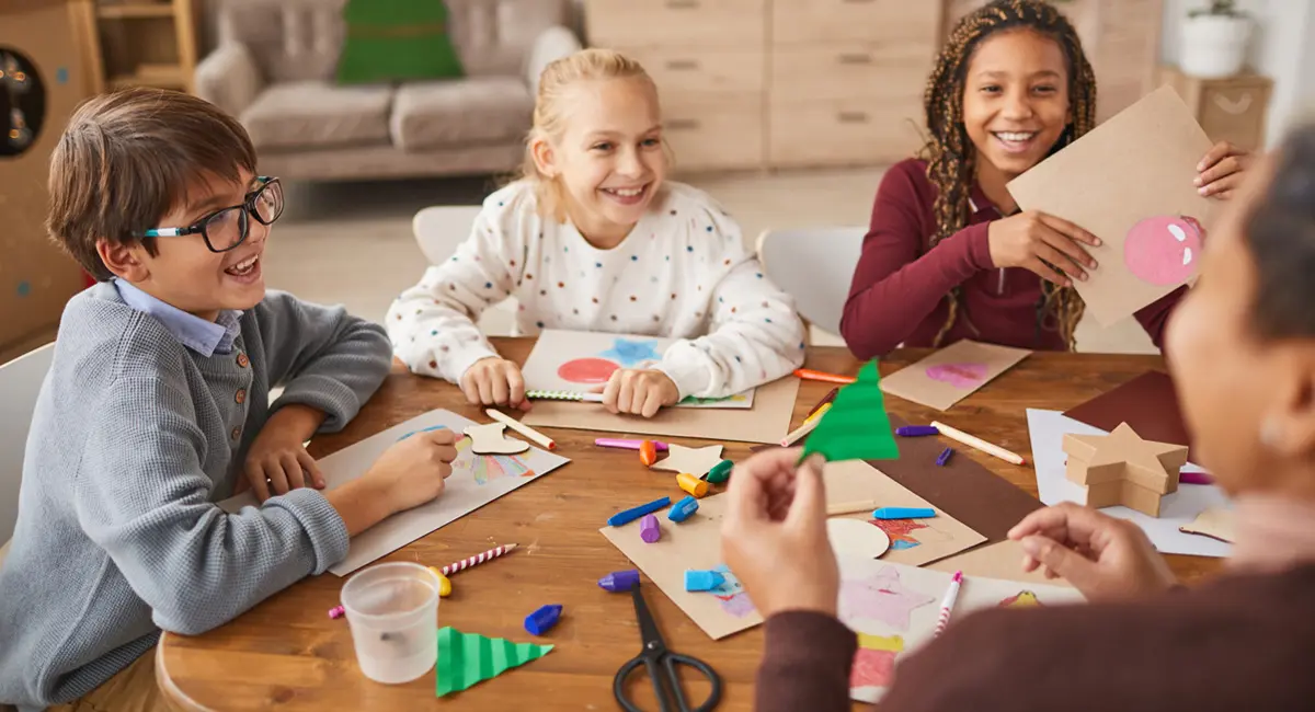 Adult showing kids how to craft Christmas decorations.