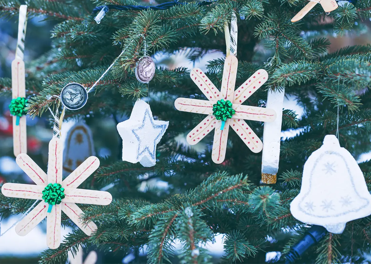 Snowflake ornaments made from popsicle sticks decorate a tree.