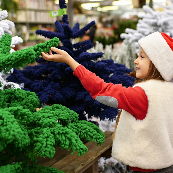 Child looking at artificial Christmas trees in a store.