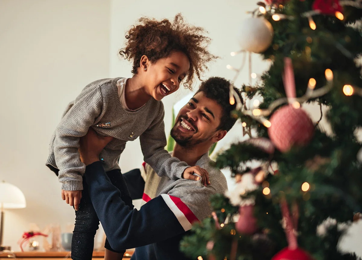 Father and daughter having fun putting up Christmas tree