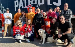 A group of people standing in front of a New England Patriots truck.