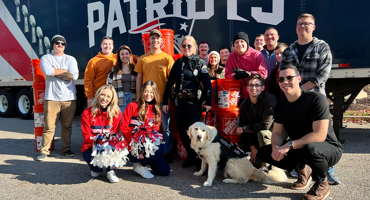 A group of people standing in front of a New England Patriots truck.