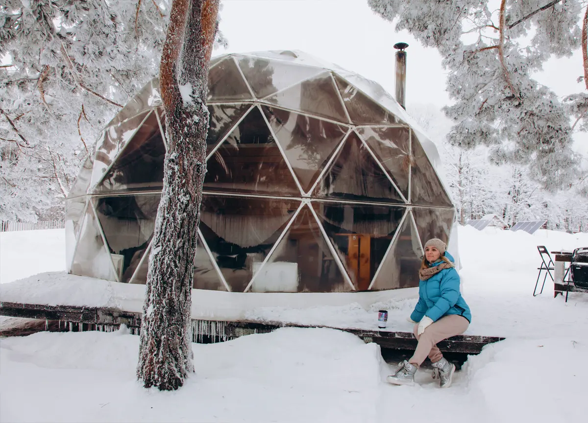 A woman sitting in front of an environmentally-friendly globe used for winter camping.