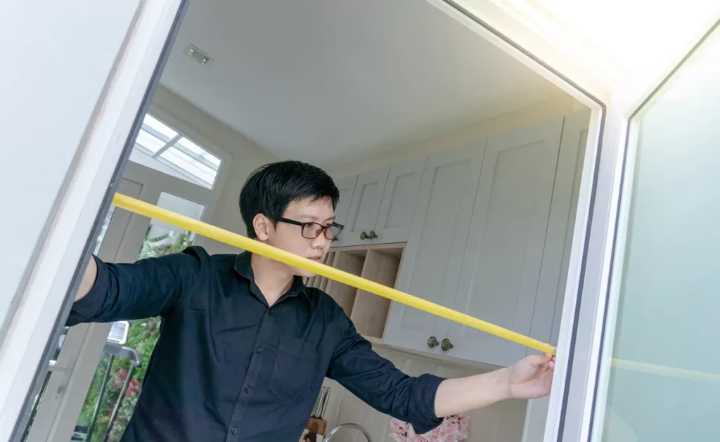 A man taking measurements of a doorway.