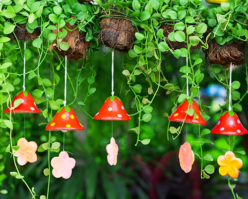 Whimsical handmade mushroom windchimes hanging in a garden.