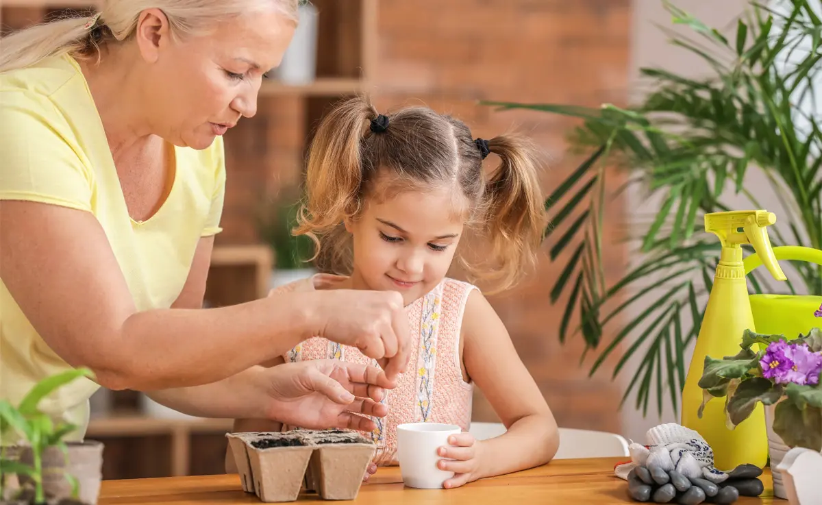 A grandmother and granddaughter planting seeds indoors.