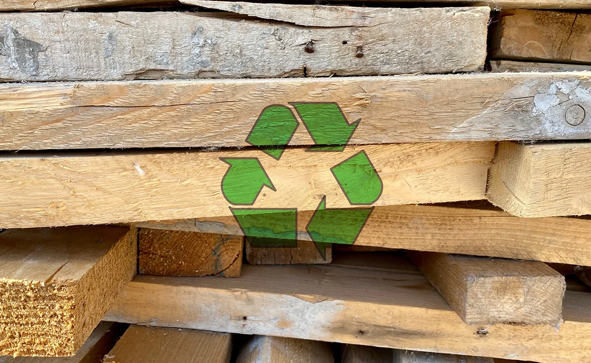 Recycling arrow icon on waste wooden piles from a construction site