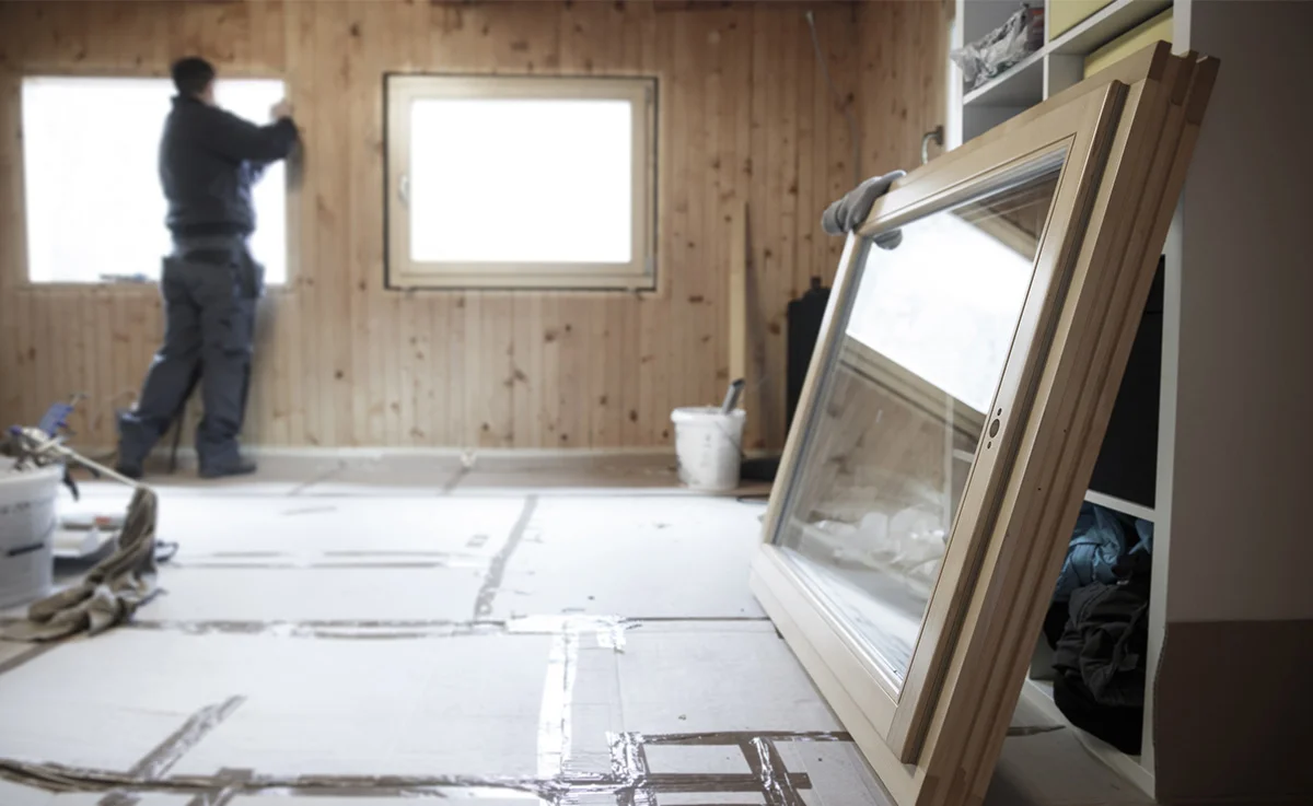A man putting in wooden windows.