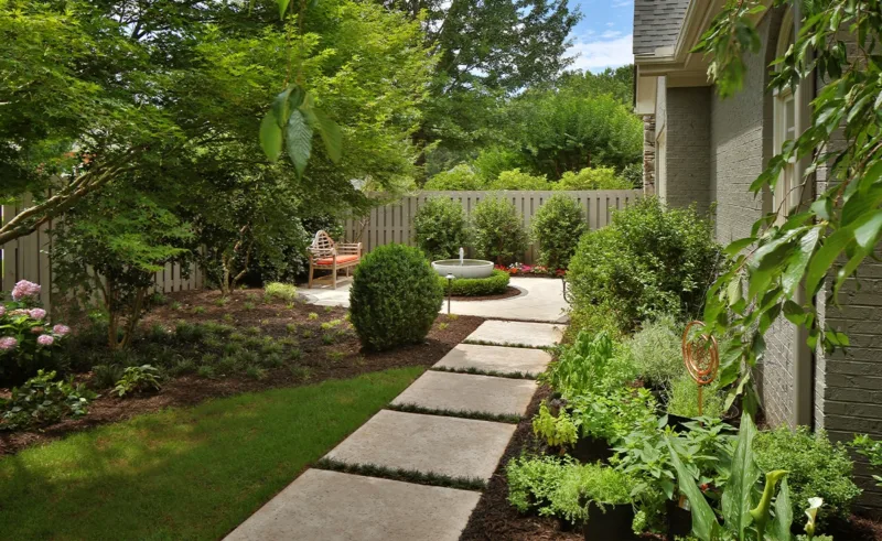 A path of large concrete squares leads to a small backyard fountain.