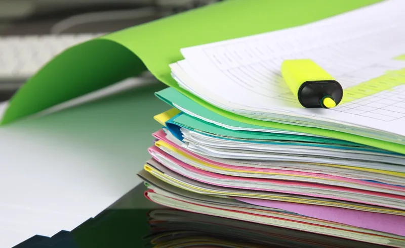 A stack of neatly organized colorful file folders and a highlighter.