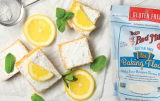 A bag of Bob’s Red Mill Gluten-Free Flour sits on a counter with lemon bars and fresh lemons.