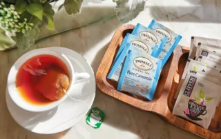 A cup of tea sits next to a small tray filled with tea bags.