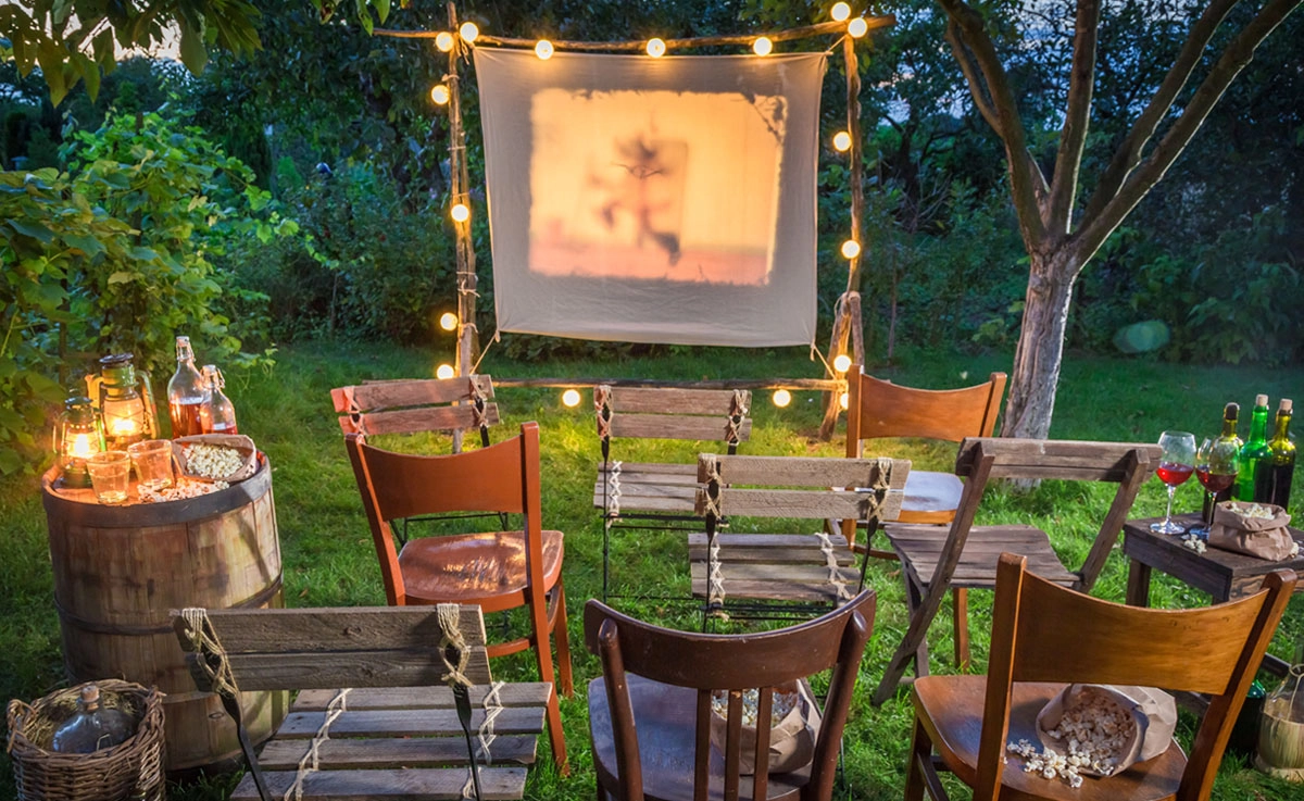 An outdoor movie setup with a retro movie projector and seating set-up