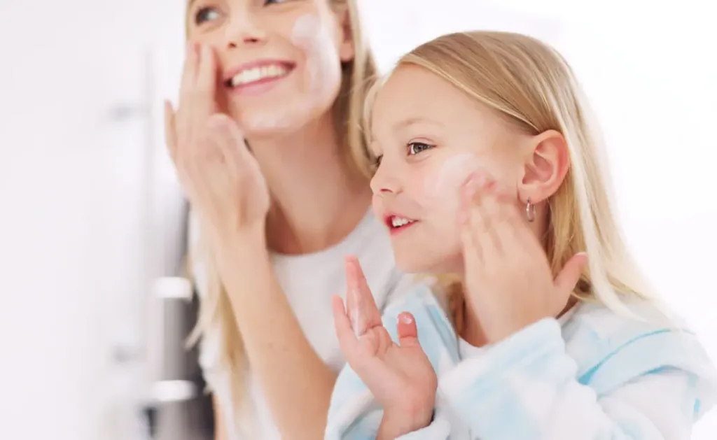 Mother and daughter sharing beauty products in the bathroom.