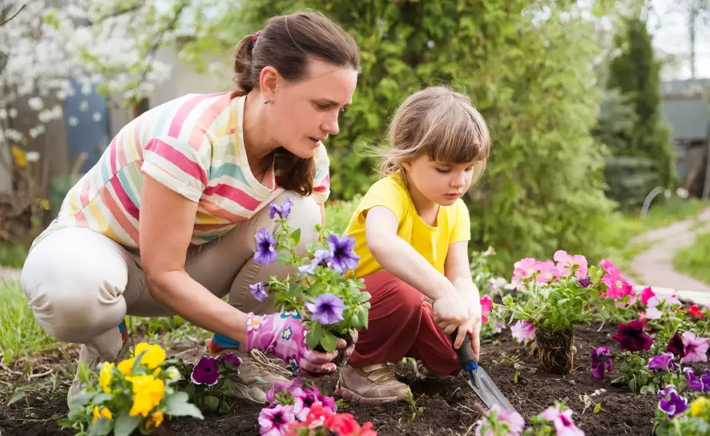 A mother and daughter gardening outside in the yard.