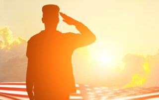 A soldier saluting at sunset at a cemetery for Memorial Day honors.